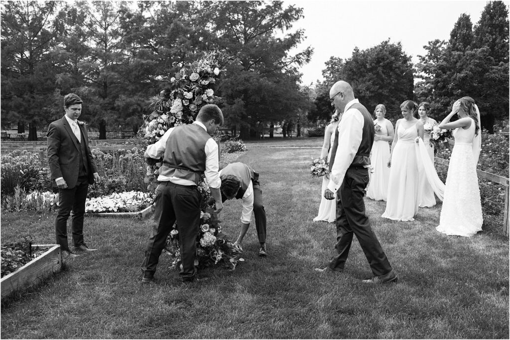 Groomsmen moving flower arch