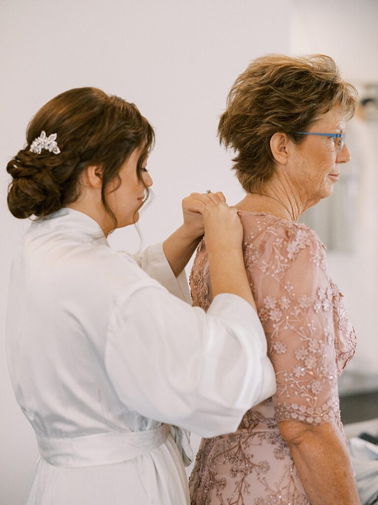 Bride helping mom into dress